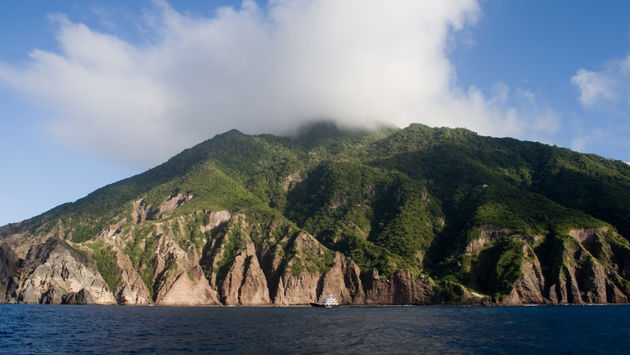 The caribic Island of Saba with on top of vulcano Mount Scenery a cloud (photo via steeric / iStock / Getty Images Plus)