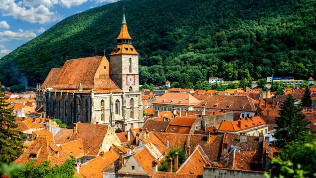 Orașul Brașov cu o catedrală neagră și un munte în fundal în România (Imagine via RossHelen/iStock/Getty Images Plus)