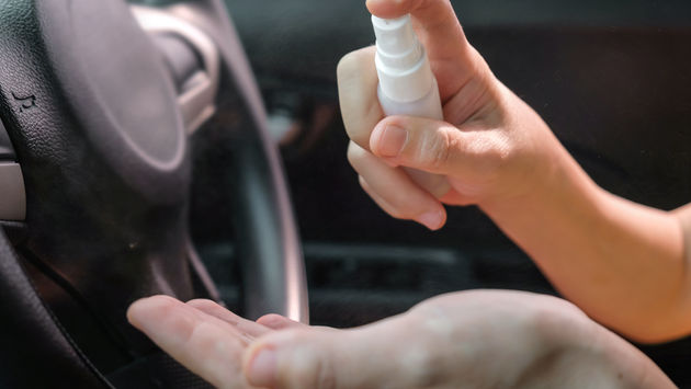 A woman using hand sanitizer before driving a rental car