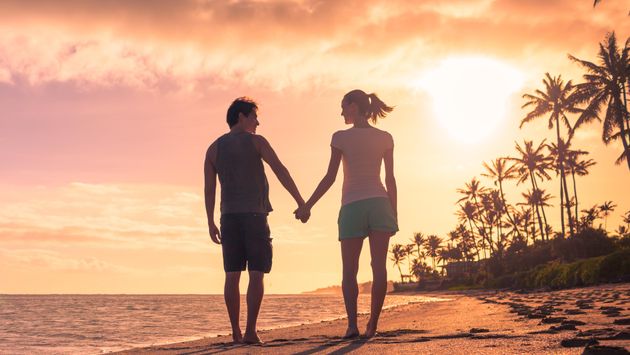 Young couple walking on the beach at sunset