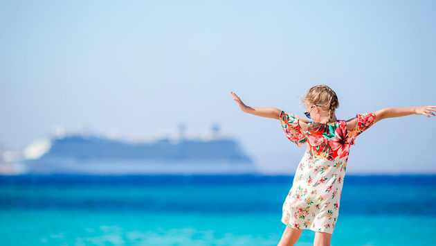 little girl at beach with cruise in background