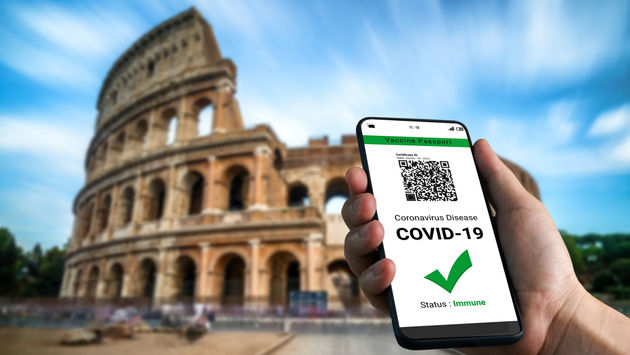 Traveler holding a digital vaccine passport in front of Rome's Colosseum.