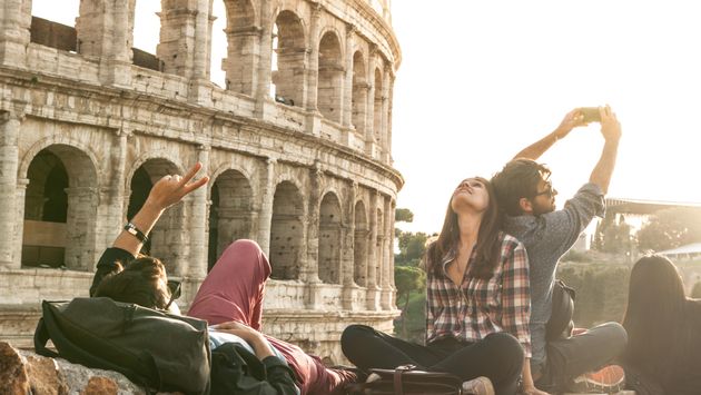 Tourists pose for selfies by the Colosseum in Rome, Italy