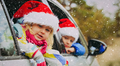 christmas car travel- happy kids travel in winter (Photo via Nadezhda1906 / iStock / Getty Images Plus)