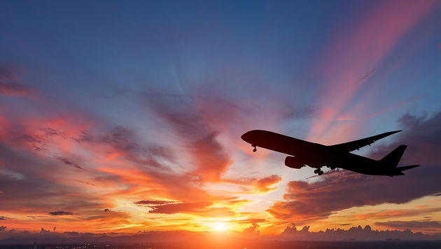 The silhouette of a passenger plane flying in sunset. (Photo via manop1984 / iStock / Getty Images Plus)