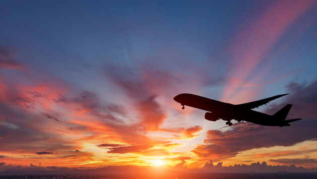 plane flying in sunset