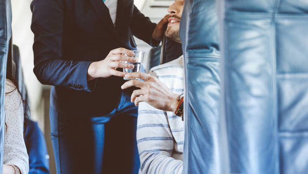 Airline hostess serving water to a passenger.