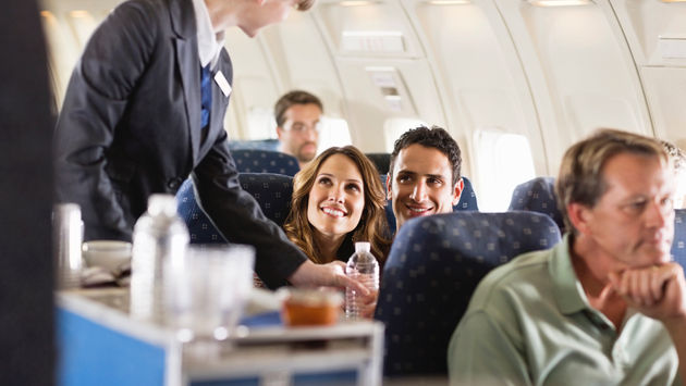 Flight attendant serving water bottles aboard an airplane.