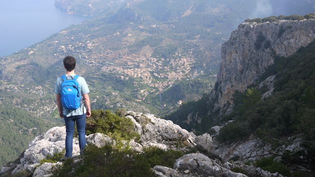 A traveler reaches the end point of On Foot Holidays’ route along Archdukes Trail in Mallorca, Spain, with Deia below