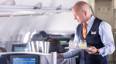 JetBlue flight attendant serving drinks in Mint section