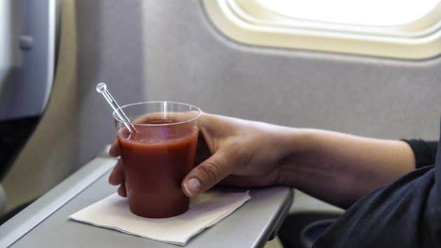 A glass of tomato juice on an airplane tray
