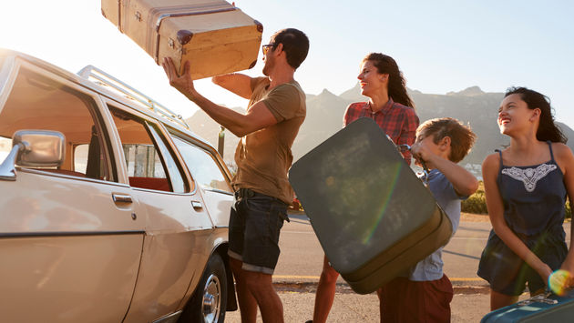 Family packing luggage for a summer road trip