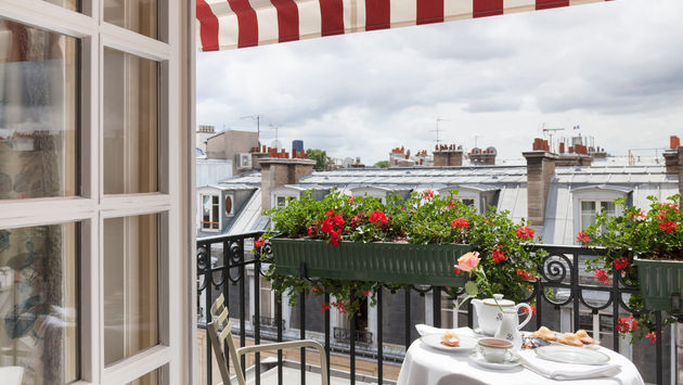 Balcony with red and white stripped awning, white tablecloths and fine china