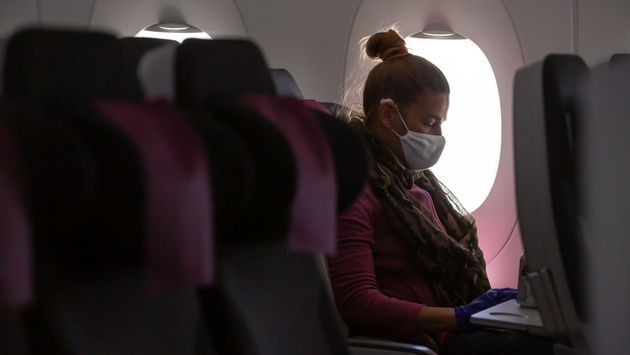 A woman wearing a face mask on an airplane