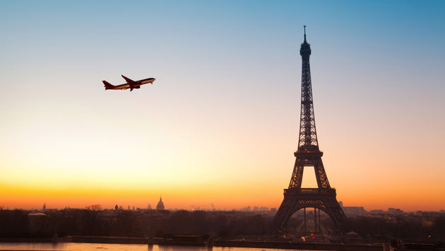 Eiffel tower at sunrise and airplane in the blue sky (Photo via anyaberkut / iStock Editorial / Getty Images Plus)