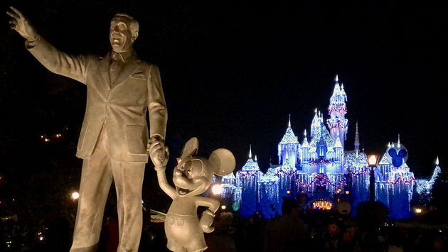 The Partners statue welcomes guests to Disneyland's Sleeping Beauty Castle dressed in glowing snow for the holidays