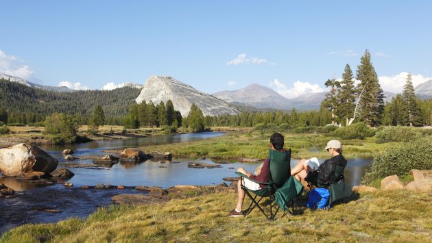 A couple relaxing on the banks of the Tuolumne River in Yosemite National Park, camping