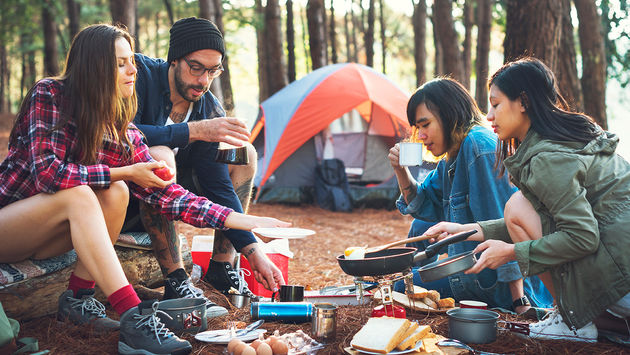 Friends camping in the forest (Photo via Rawpixel / iStock / Getty Images Plus)