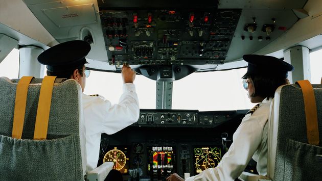 Male and female aeroplane pilot, operating controls, rear view