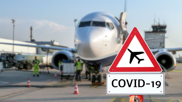 Airplane with a coronavirus warning sign concept in the foreground.