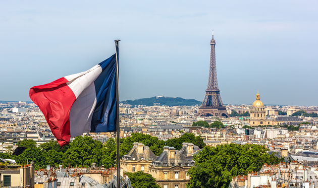 The French Flag waving with Paris and the Eiffel Tower in the background.
