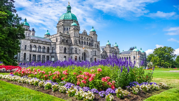 Beautiful view of historic parliament building in the citycenter of Victoria with colorful flowers on a sunny day, Vancouver Island, British Columbia, Canada (photo via bluejayphoto / iStock / Getty Images Plus)