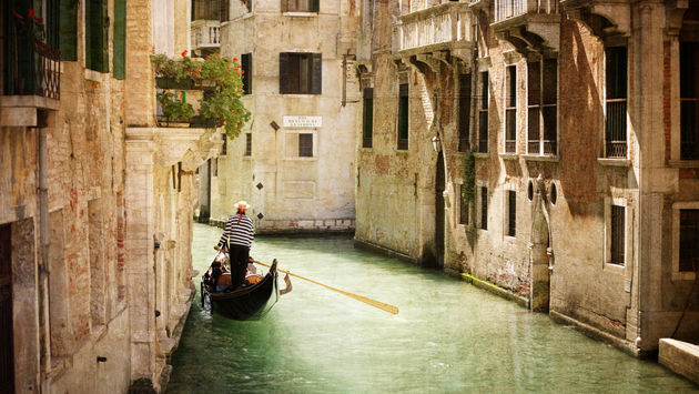 Gondola travels down the canals of Venice in Italy (photo via BrianAJackson / iStock / Getty Images Plus)